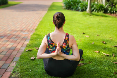 Rear view of woman sitting on field