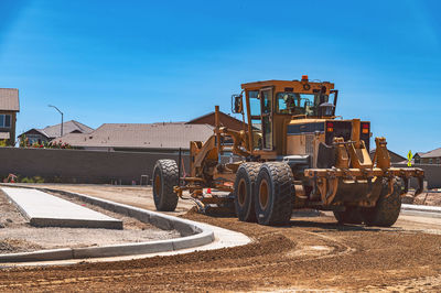 Excavator stretches small stones along the road.yellow tractor, construction equipment, road repair.