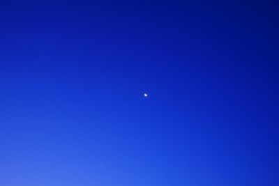 Low angle view of moon against clear blue sky