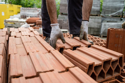 Low section of man holding bricks while standing in construction site