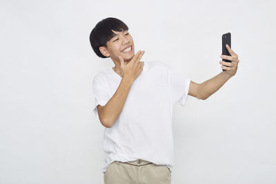 Mid adult man using smart phone against white background