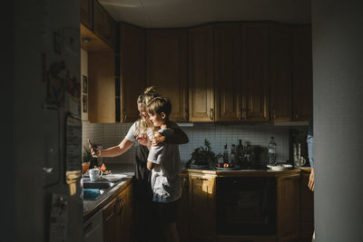 Mother and son taking selfie on smart phone in kitchen