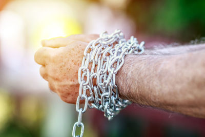 Cropped hands of man tied with chain