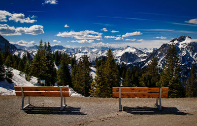 Benches on land against mountains during winter
