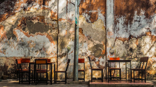 Empty chairs and table against wall in old building