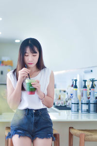 Portrait of young woman using mobile phone while sitting at home