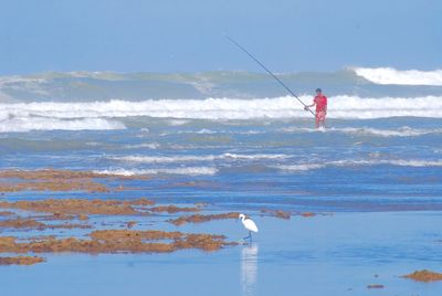 Man fishing in sea against sky