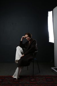 Side view of young woman sitting on wall