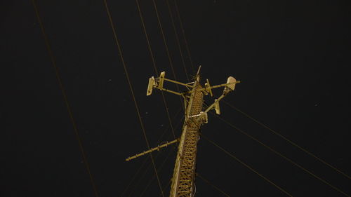 Low angle view of electricity pylon at night