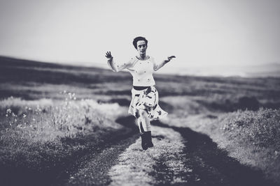 Woman with arms outstretched standing on field