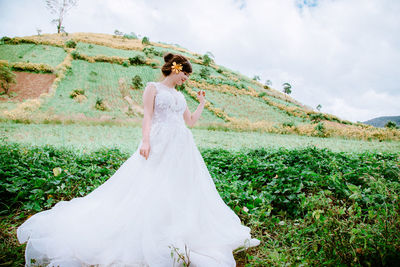 Full length of bride standing by plants against sky