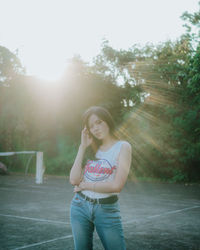 Full length of young woman standing against trees