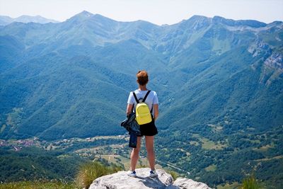 A woman looks at the valley from the top of a mountain