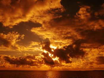 Scenic view of sea against dramatic sky during sunset