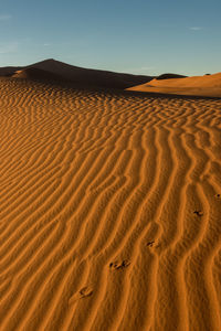 Sand dune in desert against clear sky