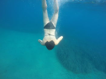 Rear view of woman swimming in blue sea