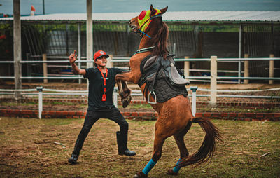 Side view of young man with horse on field