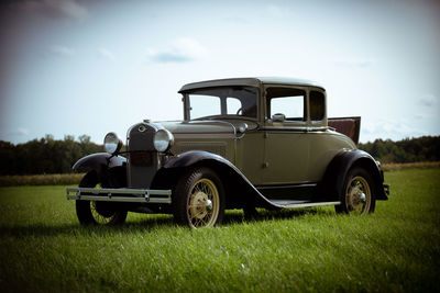 Vintage car on field against sky