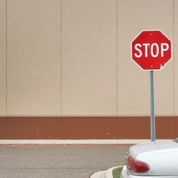 Close-up of road sign against wall