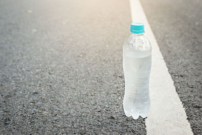 Low section of person standing by bottle on road