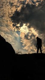 Silhouette man standing on mountain against sky during sunset