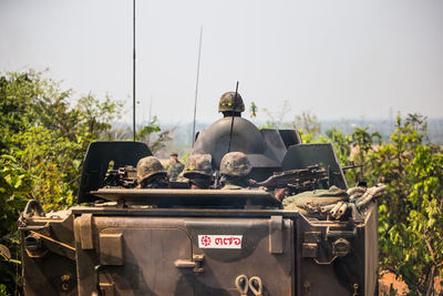 Army soldiers in armored tank against sky