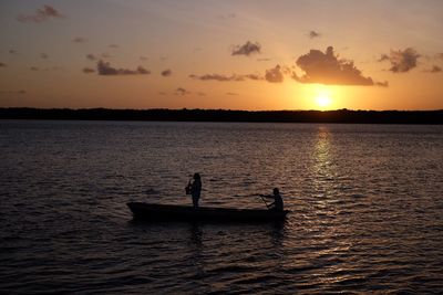 People traveling in boat sailing on sea during sunset