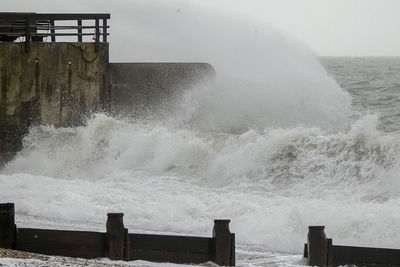 Waves splashing on shore against sky