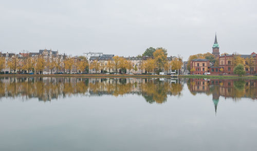 Reflection of buildings and trees in river against sky