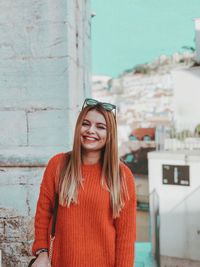 Portrait of smiling young woman standing against brick wall