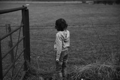 Boy standing by fence on field