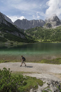 Side view of hiker walking against lake and mountains