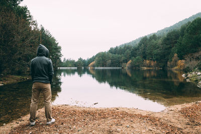 Rear view of man standing on lakeshore