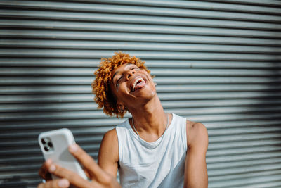 African american teenager smiling with phone.