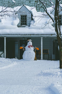 Snow covered house by building during winter