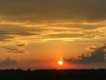 Scenic view of silhouette field against orange sky