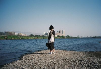 Rear view of woman standing in city against clear sky