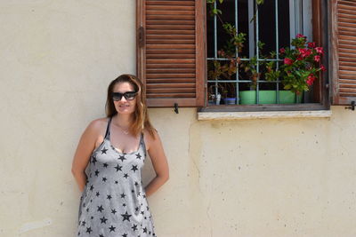 Young woman leaning by window on wall