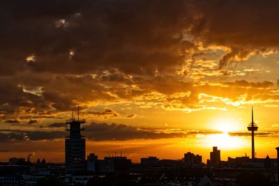 Silhouette buildings against cloudy sky during sunset