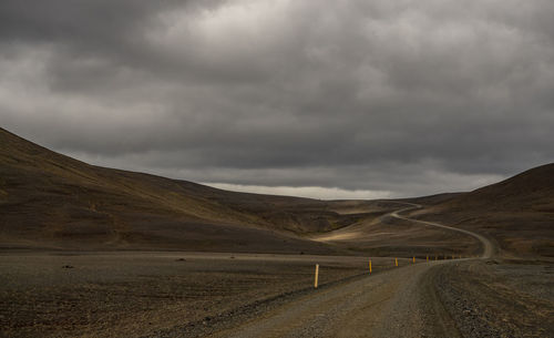 Country road along landscape against sky