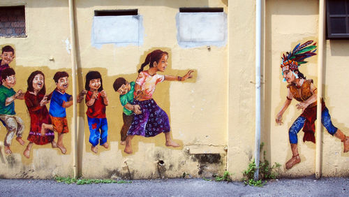 Full length of happy woman standing against building