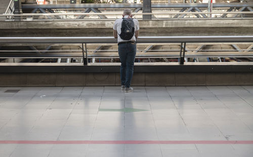 Rear view of adult man standing on railing in city