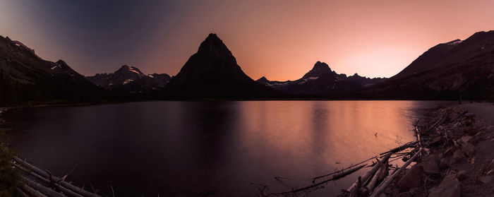 Scenic view of lake by mountains against sky during sunset