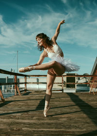 Full length of woman dancing on pier against sky