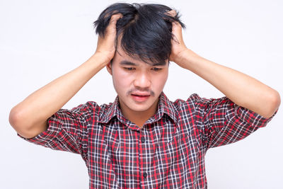 Portrait of young man standing against white background