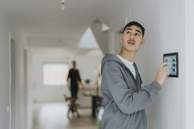 Boy using digital tablet mounted on wall while standing at smart home