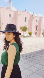 Portrait of young woman standing against building