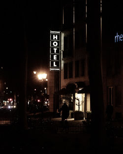 Information sign on street against building at night