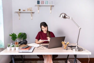 Young woman using phone while sitting on table