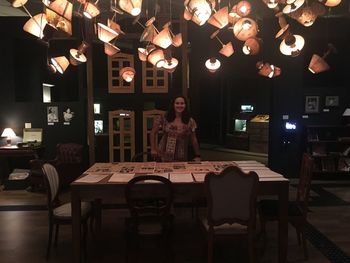 Portrait of young woman standing on table in illuminated at night